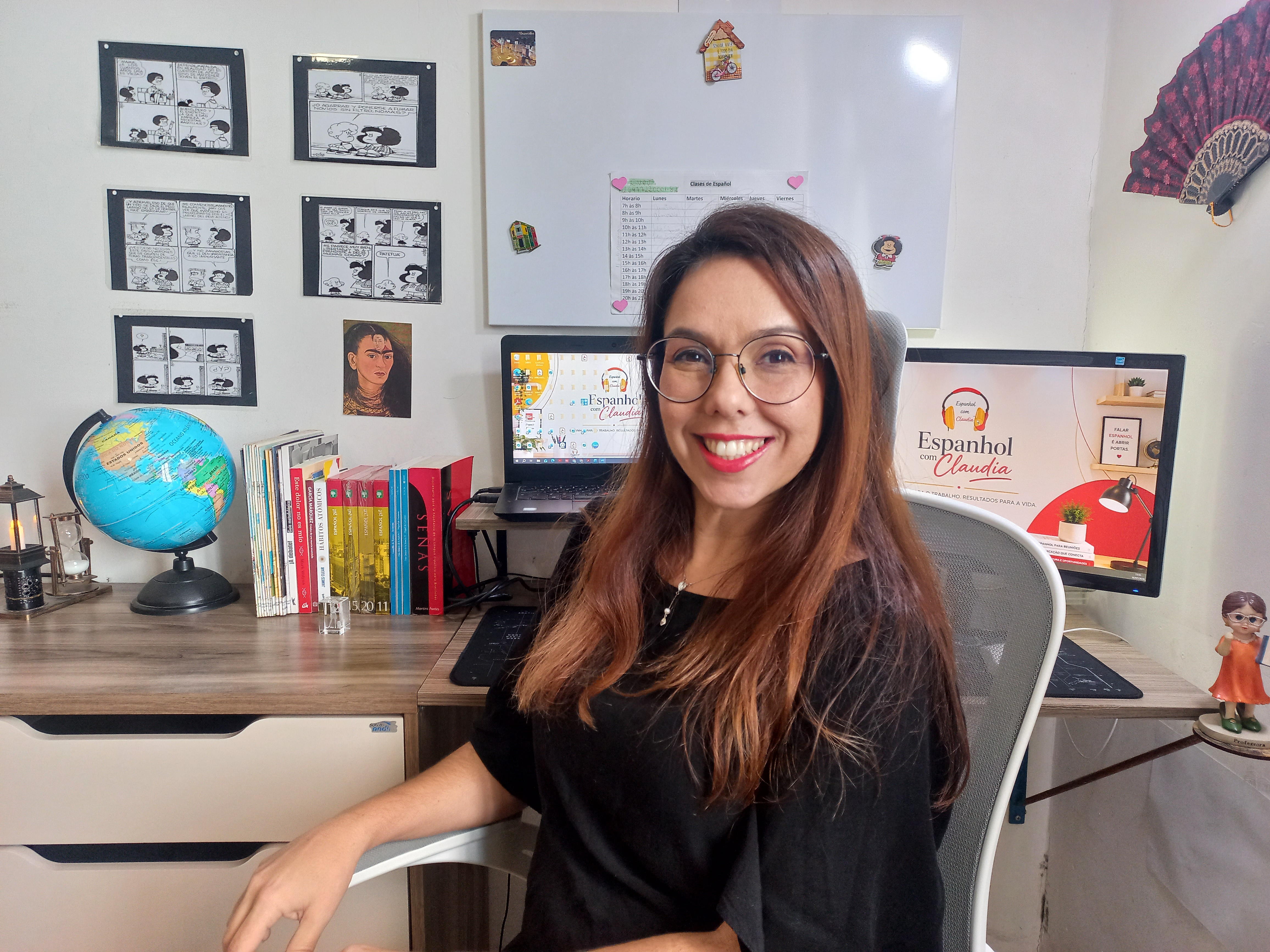 Professora Claudia sorrindo em seu ambiente de aulas